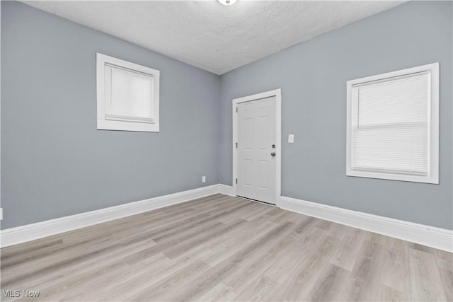 spare room with light hardwood / wood-style flooring and a textured ceiling