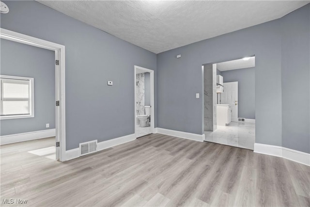 unfurnished room featuring a textured ceiling and light hardwood / wood-style flooring