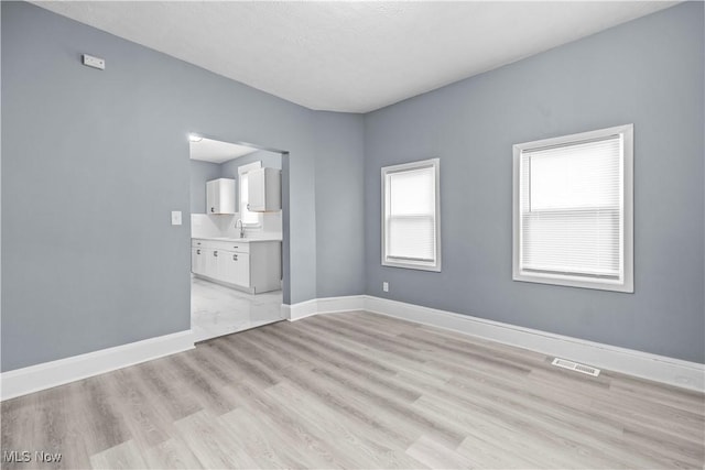 empty room with sink and light hardwood / wood-style flooring