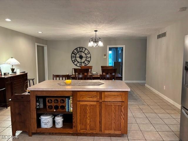 kitchen with hanging light fixtures, a kitchen island, light tile patterned floors, and a notable chandelier