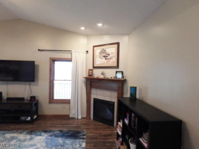 living room with a tiled fireplace, lofted ceiling, and dark hardwood / wood-style floors