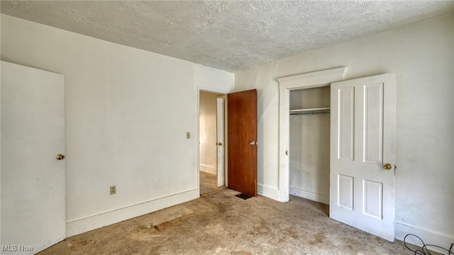 unfurnished bedroom featuring light colored carpet, a textured ceiling, and a closet