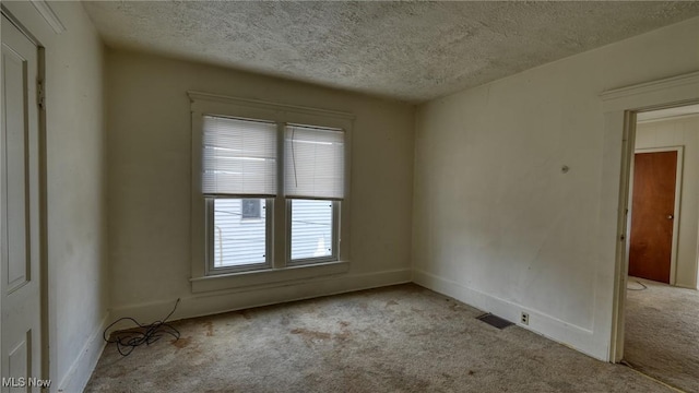 spare room with light colored carpet and a textured ceiling