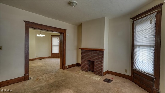 unfurnished living room featuring a brick fireplace, a healthy amount of sunlight, light carpet, and a notable chandelier