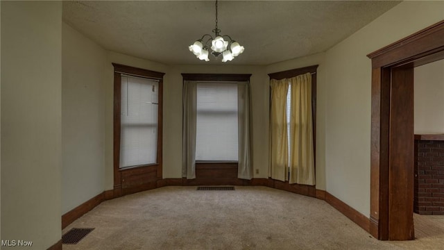 carpeted spare room featuring a notable chandelier