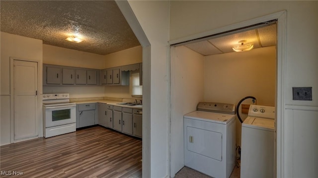 clothes washing area featuring washing machine and clothes dryer, dark hardwood / wood-style floors, sink, and a textured ceiling