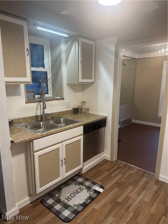 kitchen with hardwood / wood-style floors, sink, stainless steel dishwasher, and white cabinets