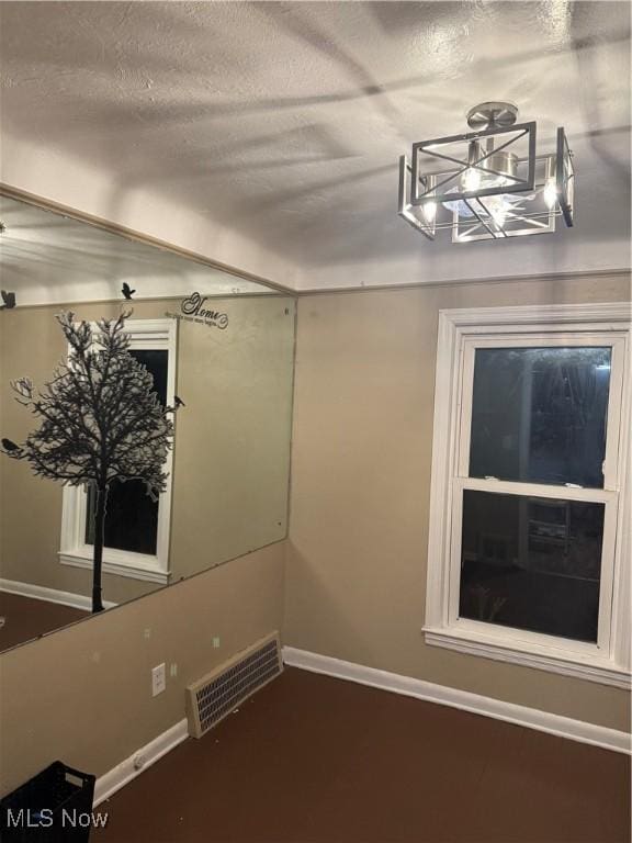 empty room featuring a textured ceiling and a notable chandelier