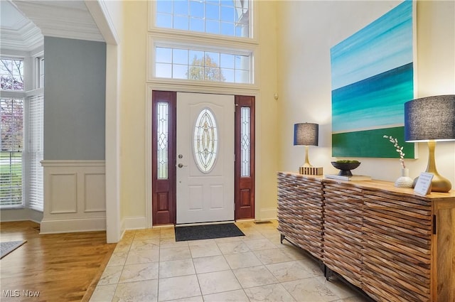 entrance foyer with a high ceiling, crown molding, and light hardwood / wood-style floors