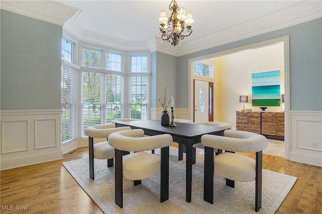 dining area with crown molding, an inviting chandelier, and light hardwood / wood-style floors