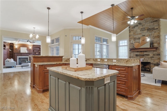 kitchen with gray cabinets, a kitchen island, a fireplace, hanging light fixtures, and light stone countertops