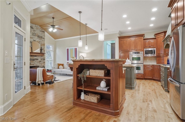 kitchen with a stone fireplace, stainless steel appliances, ornamental molding, a kitchen island, and decorative light fixtures