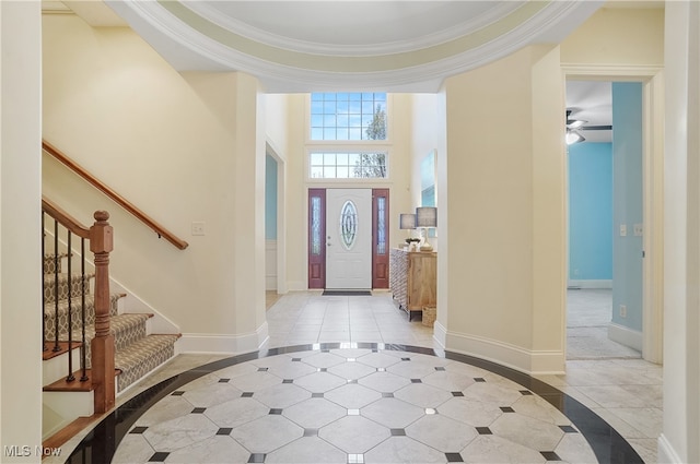 entryway featuring crown molding, a towering ceiling, and light tile patterned floors