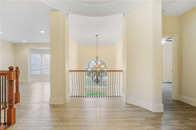 hall with a notable chandelier, ornamental molding, and light hardwood / wood-style floors