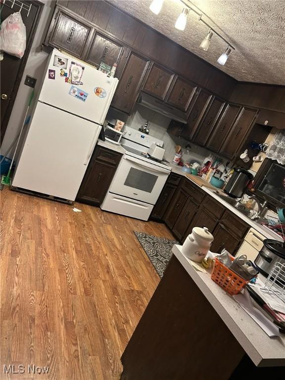 kitchen featuring white appliances, light hardwood / wood-style flooring, dark brown cabinets, and a textured ceiling