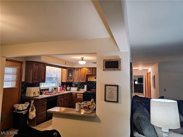 kitchen with sink, tasteful backsplash, light tile patterned floors, kitchen peninsula, and black appliances