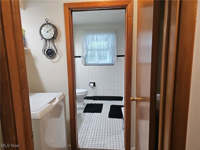 bathroom featuring tile walls, tile patterned floors, and toilet