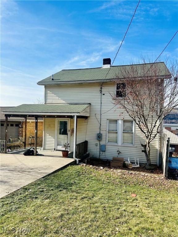 back of property with a yard and a patio