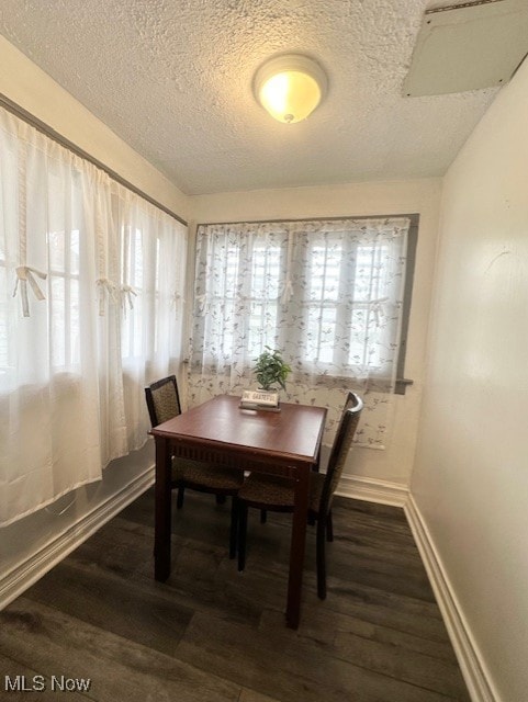 dining area featuring a textured ceiling and dark hardwood / wood-style flooring