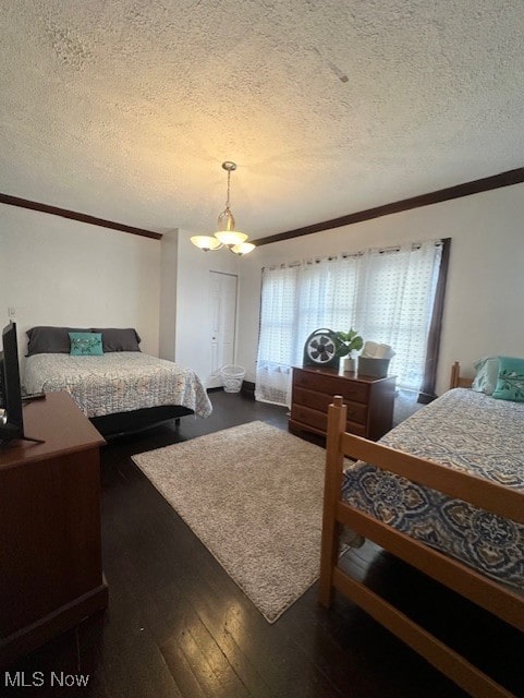 bedroom with ornamental molding, dark hardwood / wood-style floors, a textured ceiling, and an inviting chandelier