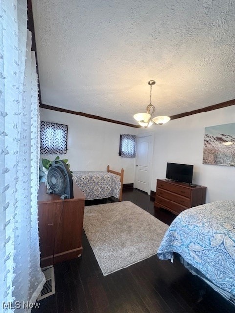 bedroom featuring crown molding, dark hardwood / wood-style floors, a textured ceiling, and a notable chandelier