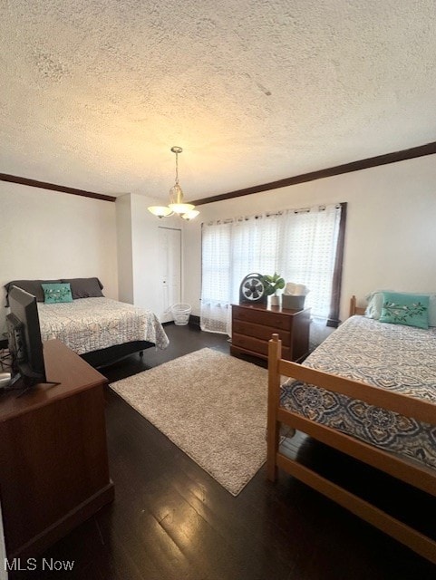 bedroom with an inviting chandelier, crown molding, dark wood-type flooring, and a textured ceiling