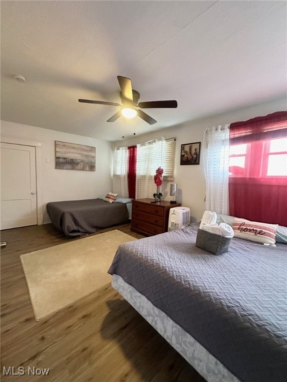 bedroom with multiple windows, dark wood-type flooring, and ceiling fan