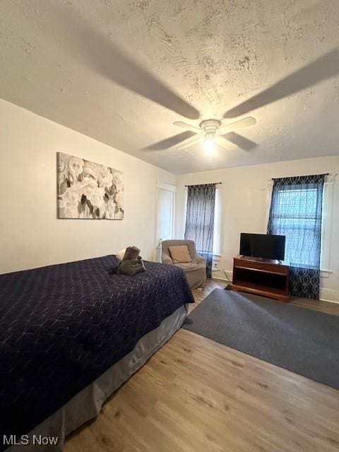 bedroom with ceiling fan, wood-type flooring, and a textured ceiling