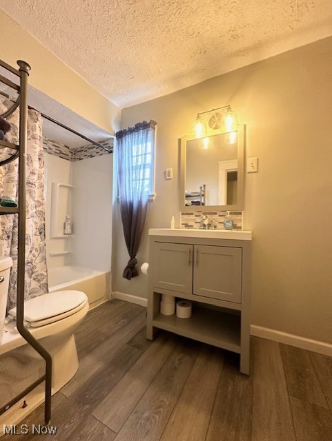 full bathroom featuring toilet, a textured ceiling, vanity, shower / bath combo with shower curtain, and hardwood / wood-style flooring