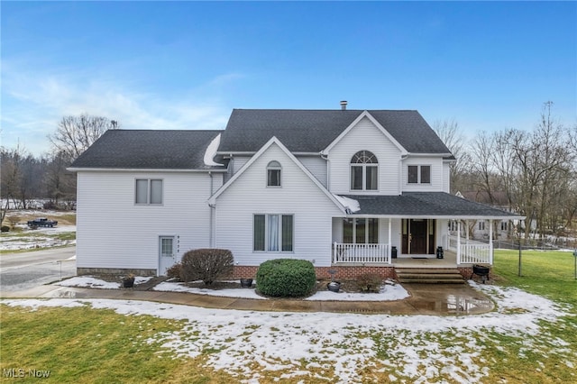 snow covered property featuring a porch and a yard