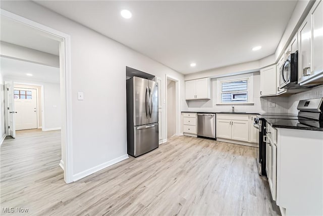 kitchen with sink, white cabinetry, stainless steel appliances, tasteful backsplash, and light wood-type flooring