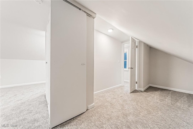 bonus room with light colored carpet and vaulted ceiling