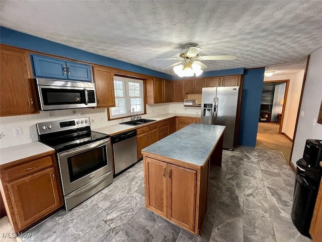 kitchen featuring sink, a textured ceiling, a kitchen island, ceiling fan, and stainless steel appliances