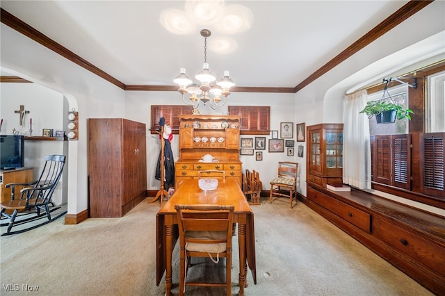 dining space with ornamental molding, light carpet, and a notable chandelier