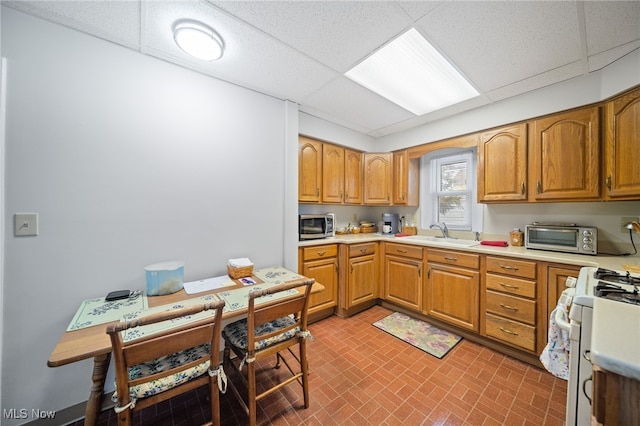 kitchen featuring sink, a paneled ceiling, and gas range gas stove