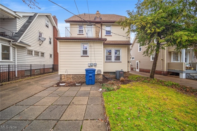 rear view of house featuring cooling unit and a yard