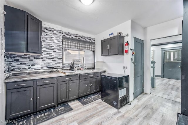 kitchen featuring sink, light hardwood / wood-style floors, and backsplash