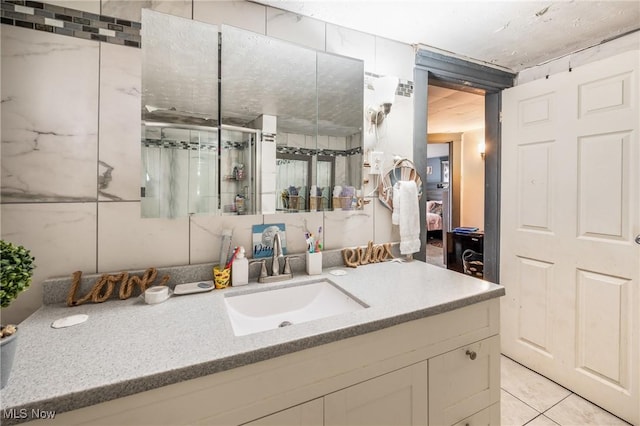 bathroom featuring tile patterned floors, vanity, a shower with shower door, and tile walls