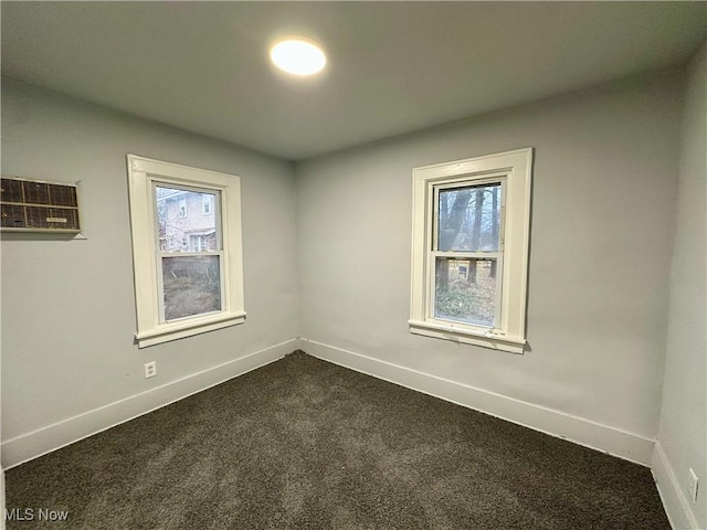 unfurnished room with dark carpet and an AC wall unit