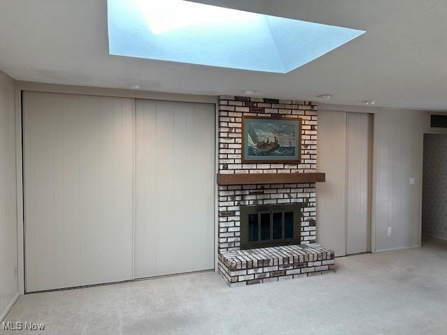 unfurnished living room featuring a brick fireplace and light colored carpet