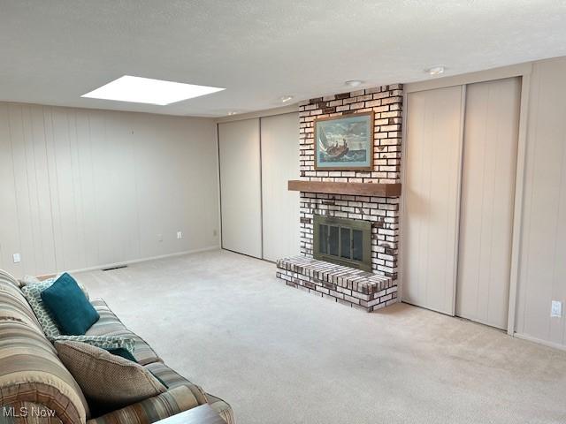 carpeted living room with a skylight, a brick fireplace, and a textured ceiling