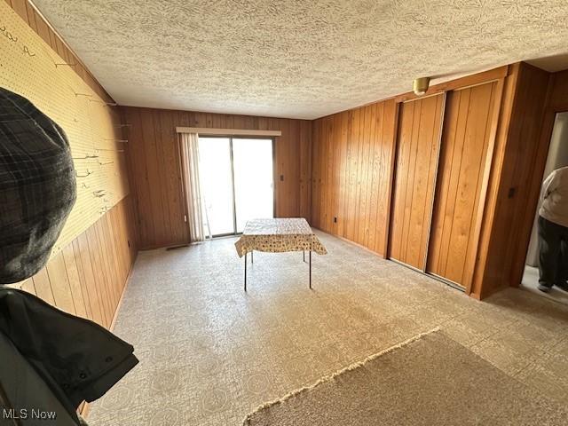 miscellaneous room featuring a textured ceiling and wooden walls