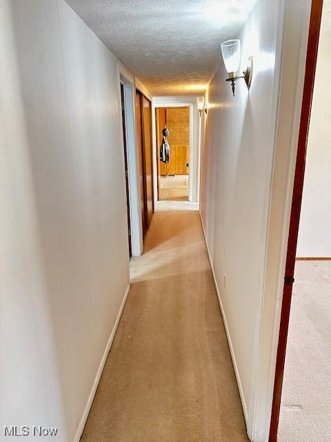 hallway featuring light carpet and a textured ceiling