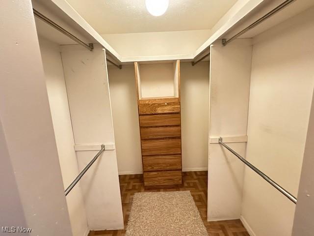 walk in closet with parquet floors