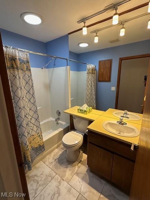 full bathroom featuring vanity, shower / tub combo with curtain, and toilet