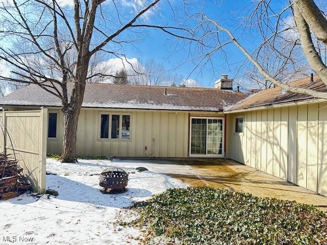 snow covered back of property with a patio area and an outdoor fire pit