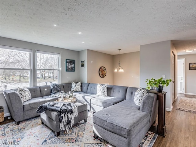 living room featuring a textured ceiling, a chandelier, and light wood-type flooring