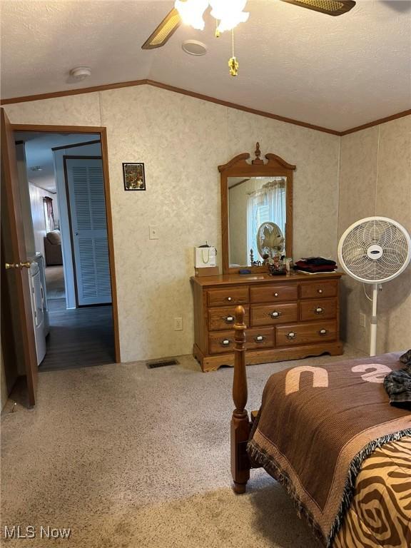 bedroom featuring lofted ceiling, crown molding, a textured ceiling, carpet floors, and ceiling fan