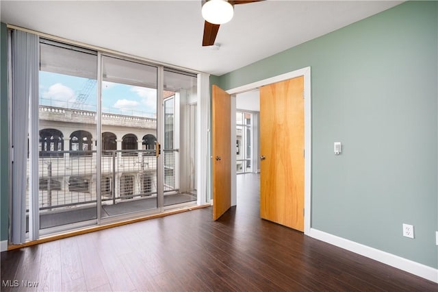 empty room featuring expansive windows, ceiling fan, and dark hardwood / wood-style flooring