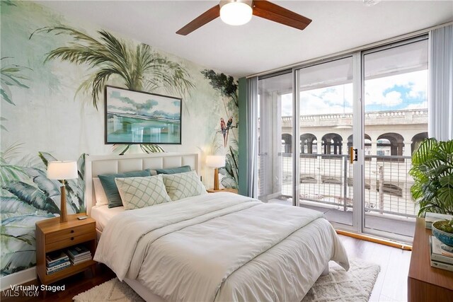 bedroom featuring a ceiling fan, wood finished floors, expansive windows, and access to outside
